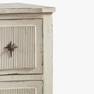 Close up of Aged white side table with two drawers and star shaped pulls on a white background