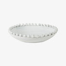 Shallow White ceramic bowl with decorative white balls around rim on a white background