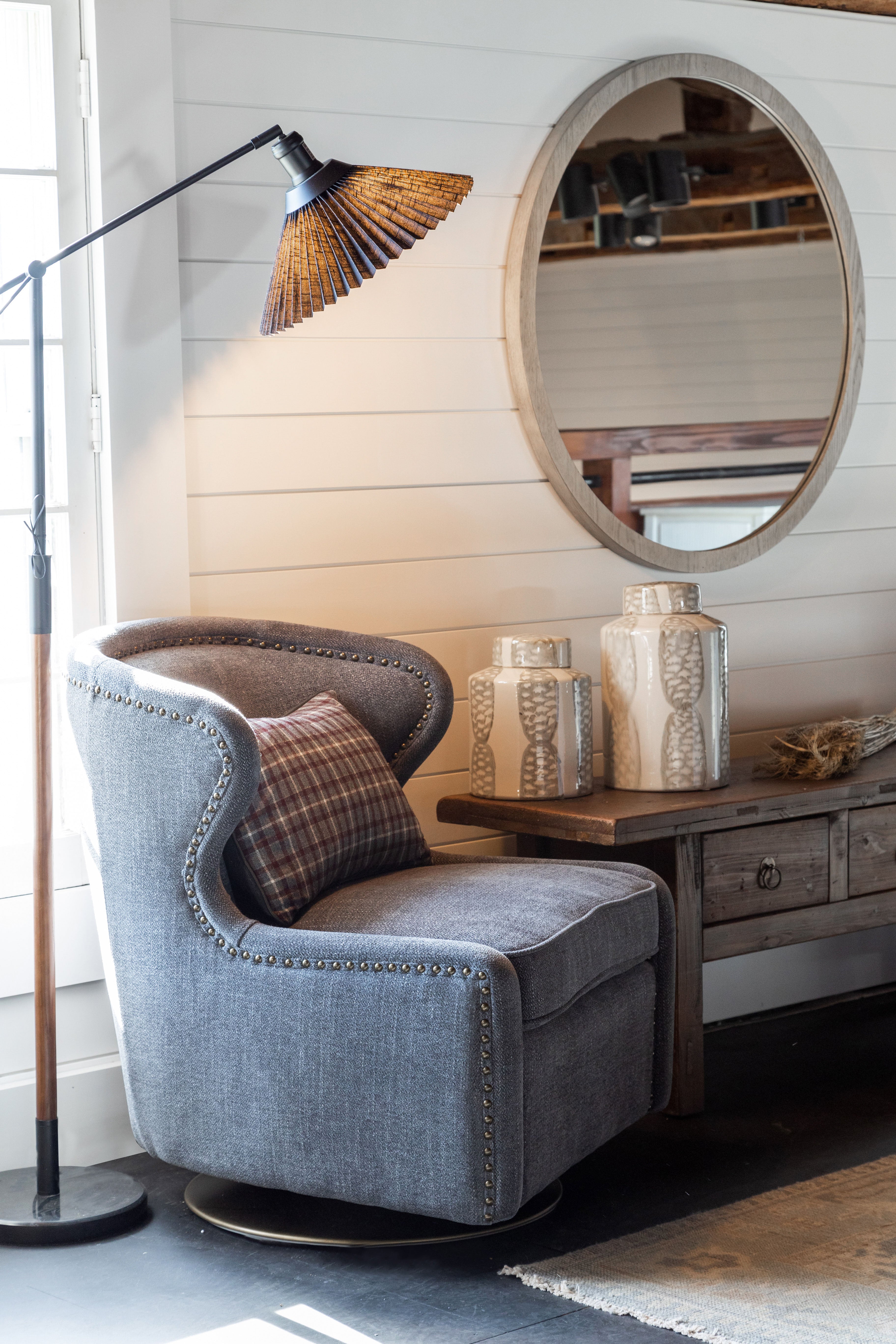 Room with lamp and blue swivel chair with mirror on wall and wood coffee table against white wall 