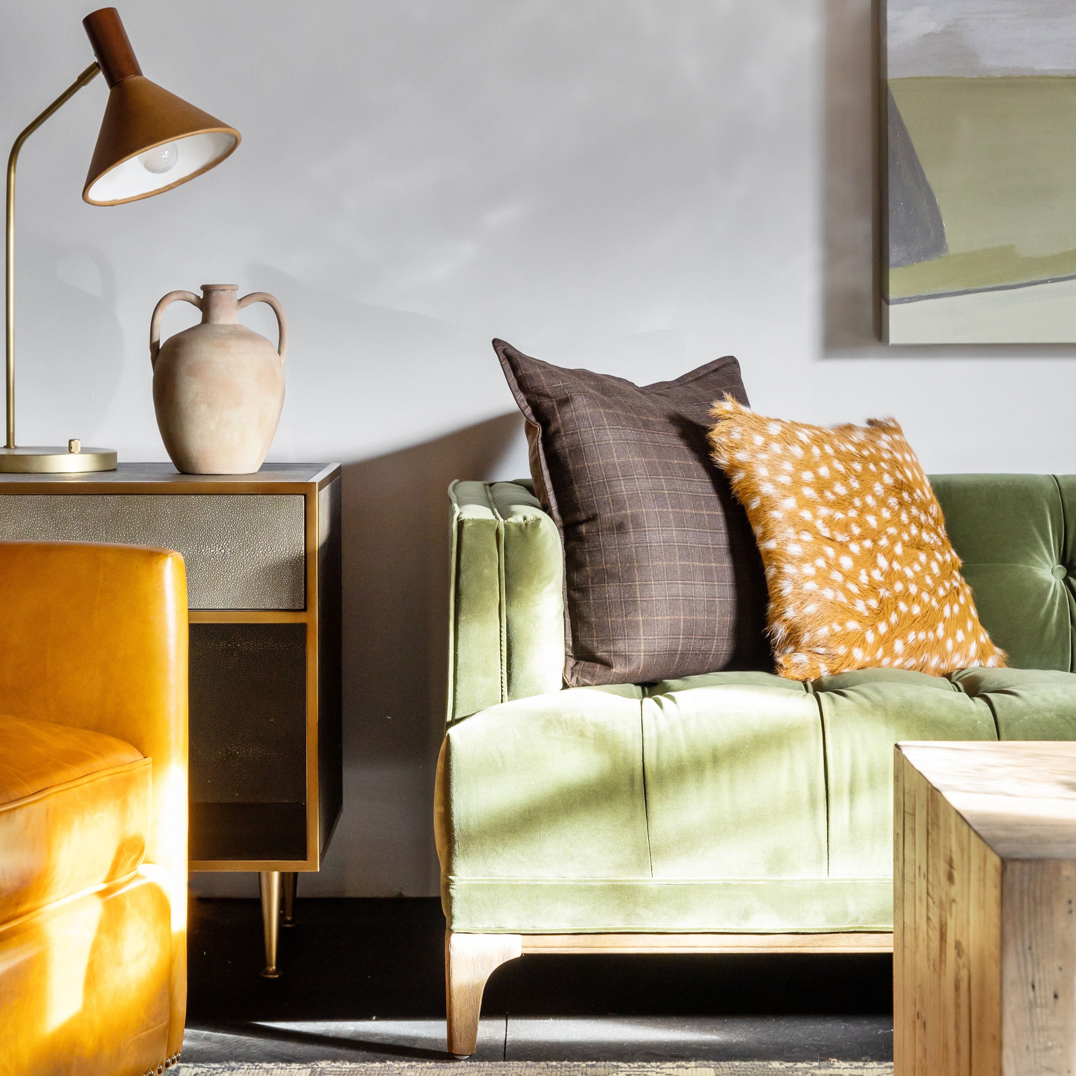 Grey shagreen nightstand with brass trim accents by four hands furniture in a living room with green sofa painting hanging above