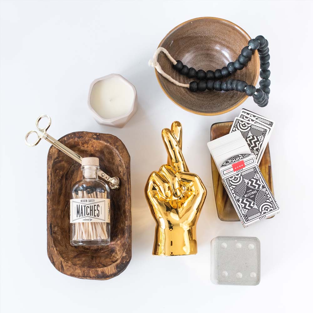 Collection of accessories including a candle wick trimmer in wooden bowl on a white background