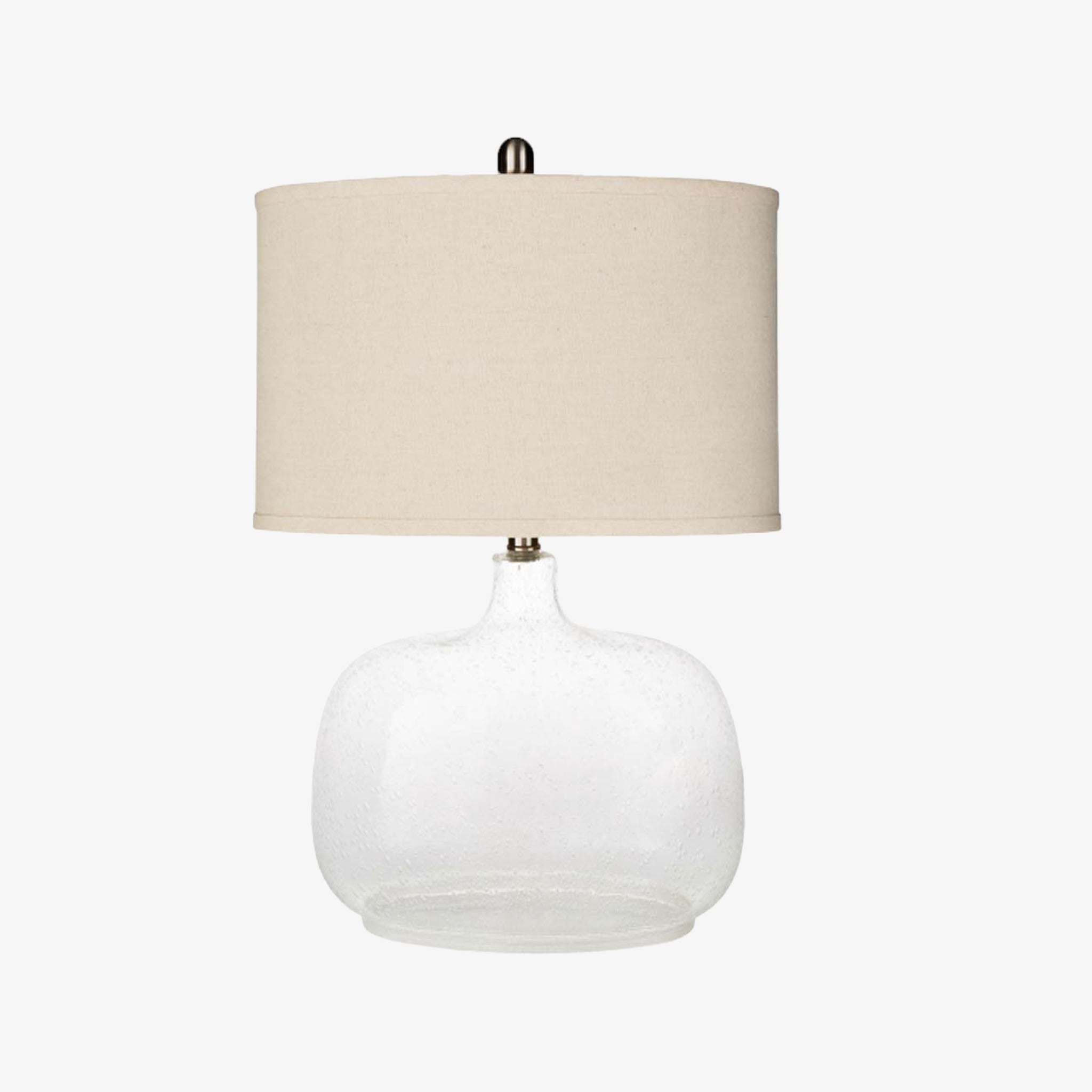 Surya brand Bentley table lamp with glass base and beige linen shade on a white background