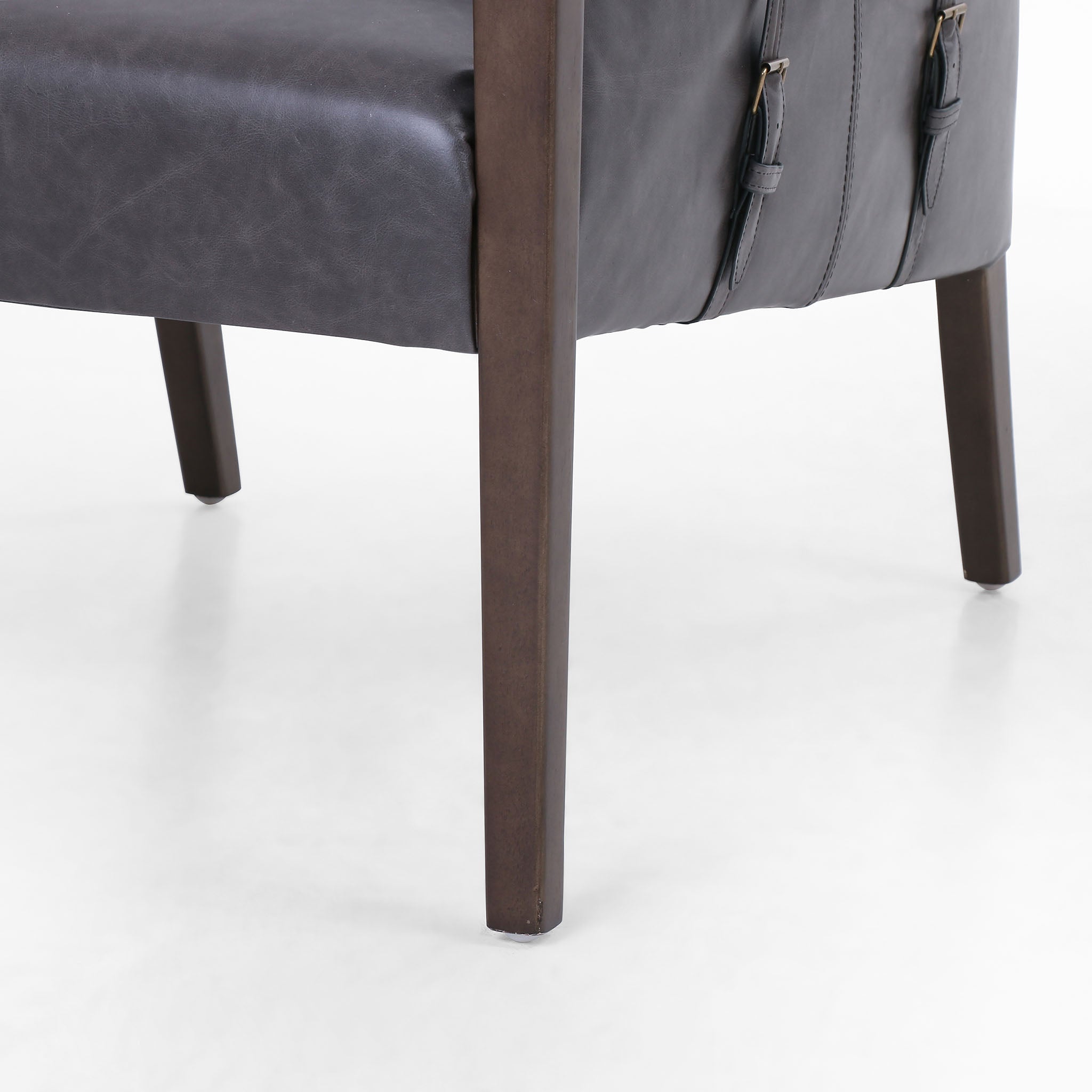 Four Hands Furniture brand Bauer chair in chaps ebony with stained wood legs and leather buckled straps on a white background