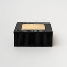 Black decorative box with ridges and small brass rectangular iinlay