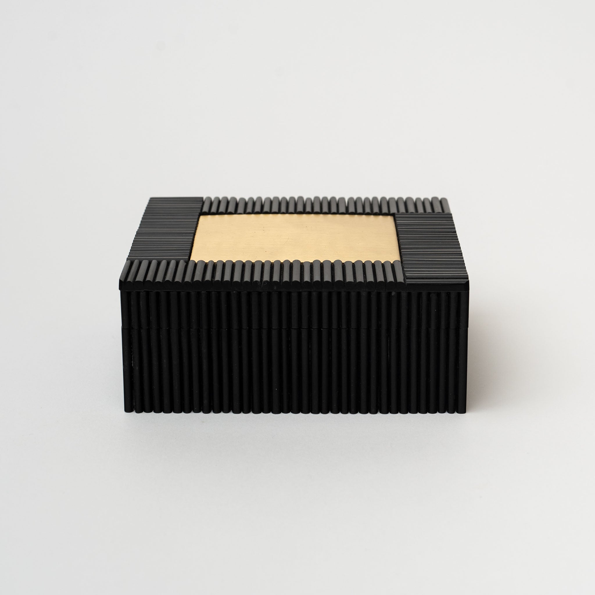 Black decorative box with ridges and small brass rectangular iinlay