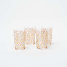 Set of four tea glasses with white and gold blossom design on a white background