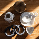 Collection of decorative house accessories including white stoneware heart dish on a wood surface  