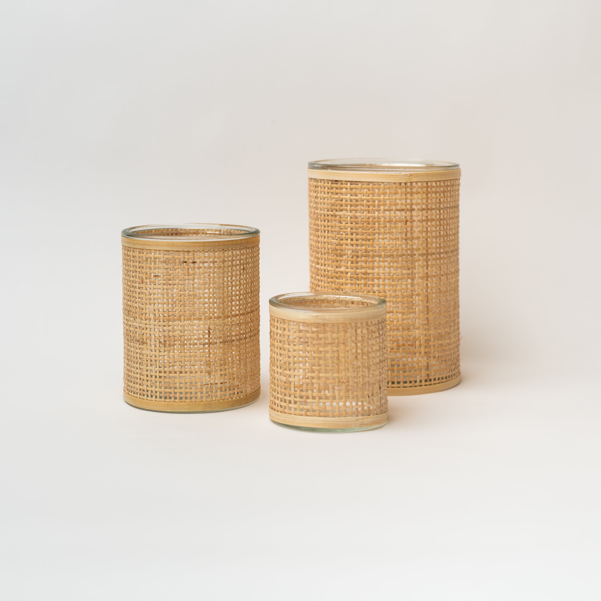 Set of three rattan wrapped vases on a white background