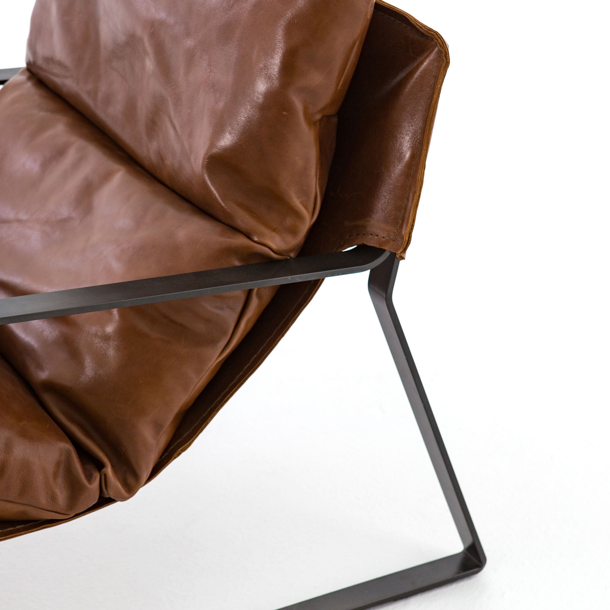 Close up of Tobacco brown leather 'Emmett' sling chair by Four hands furniture with iron frame