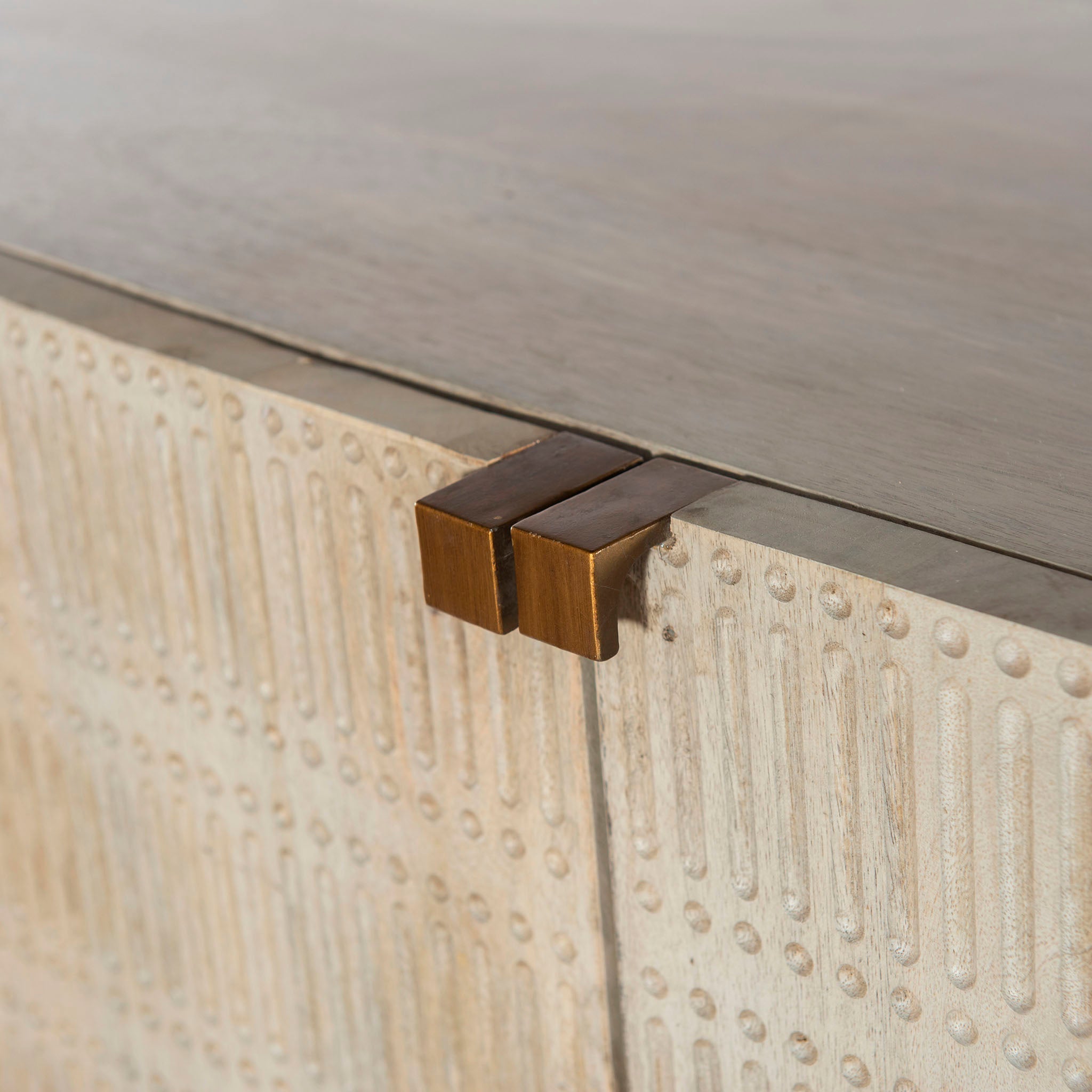 Close up of Kelby Light wood bar cabinet with carved doors and black iron frame base by four hands on a white background