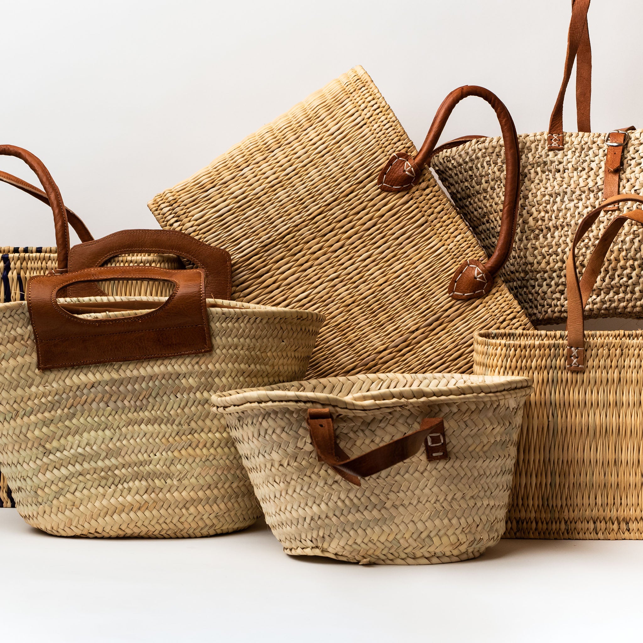 Collection of straw summer bags with leather straps on a white background