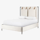 Upholstered 'Leigh' bed by Four hands furniture with metal frame and buckled head board panels on a white background