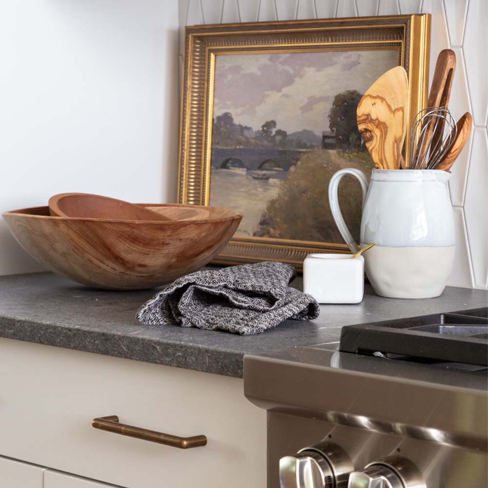 Wood salad bowls on a stone counter with painting and pitcher