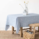 Light blue linen tablecloth on a table with sisal rug and bench