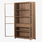 Four hands furniture brand Millie oak cabinet with glass doors and four shelves and interior drawer on a white background