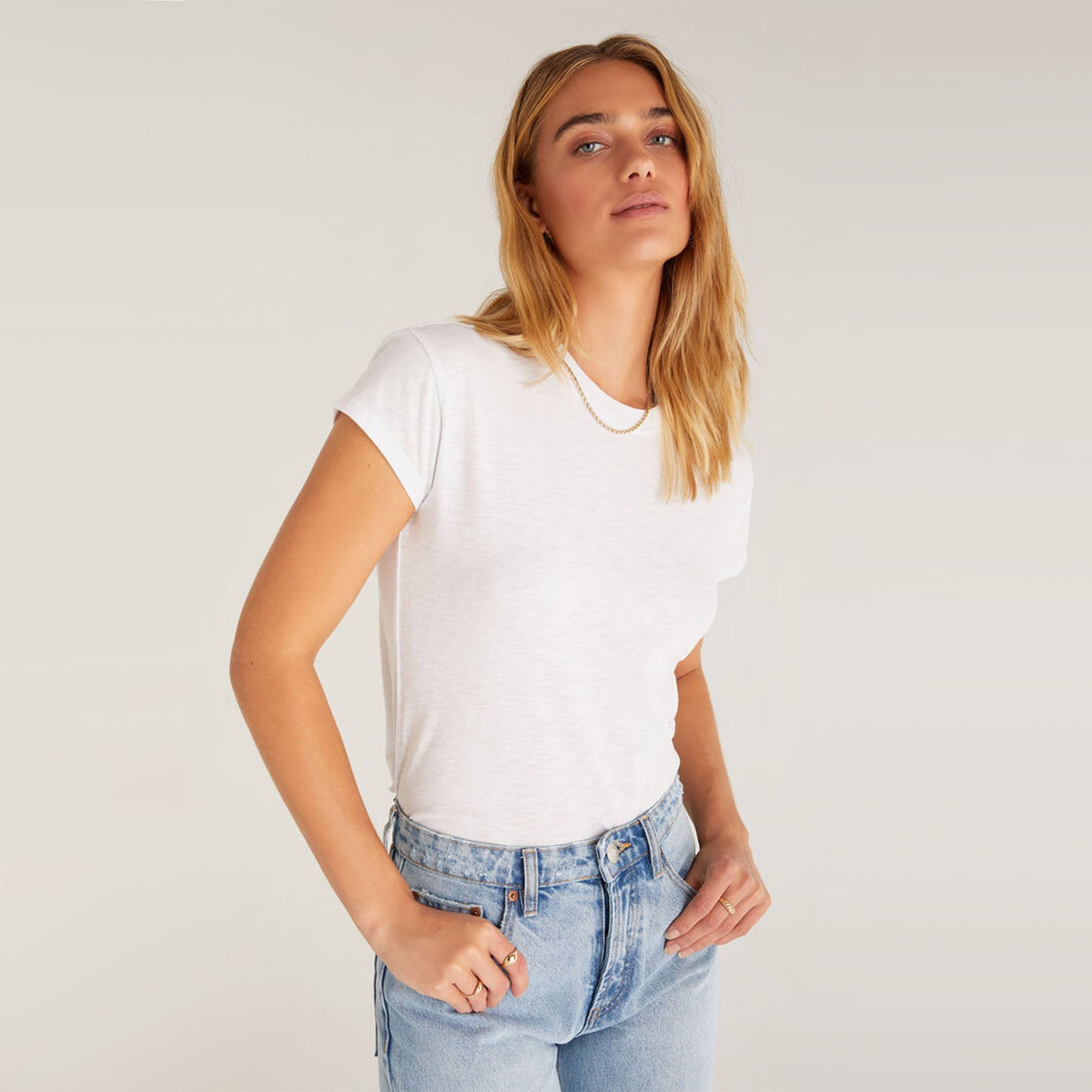 Model wearing jeans and Z supply modern slub white t shirt in front of a white background