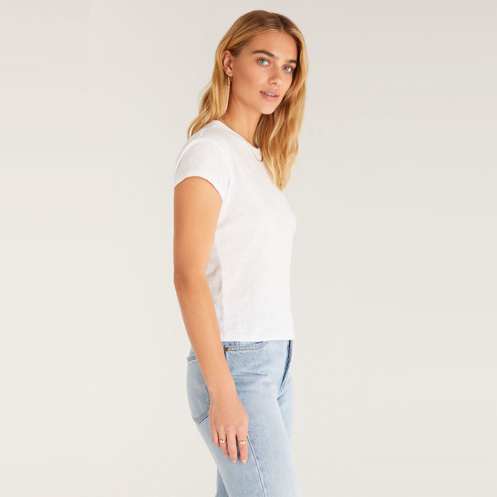 Model wearing jeans and Z supply modern slub white t shirt in front of a white background