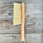 Wood brush with sisal bristles and white hanging cord on a wood table