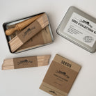 Seed collecting kit in metal tin with seed labels and envelopes on a white background