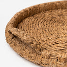 Round seagrass tray with handles on a white background