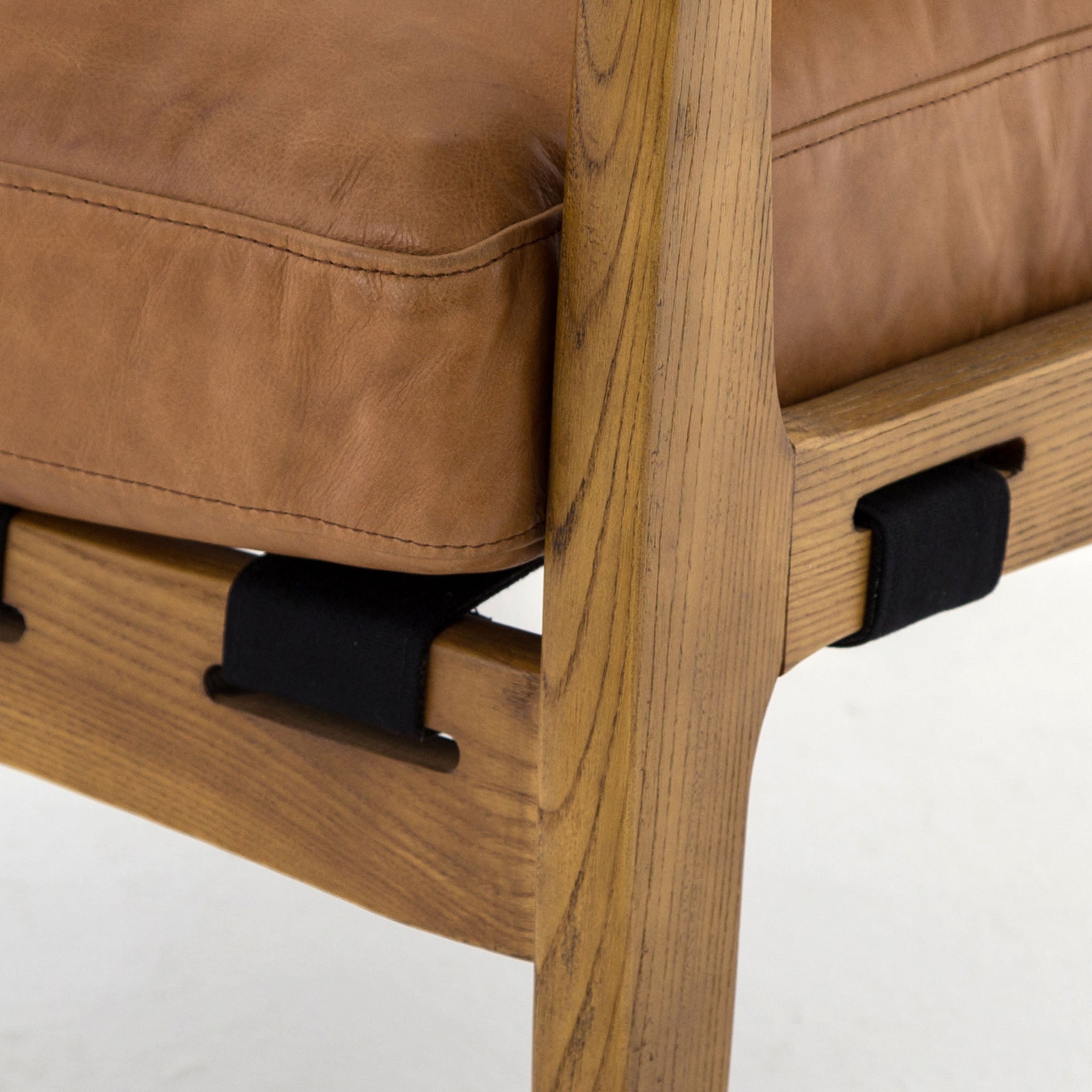 Four hands brand Silas arm chair with wood frame and patina copper leather cushions on a white background