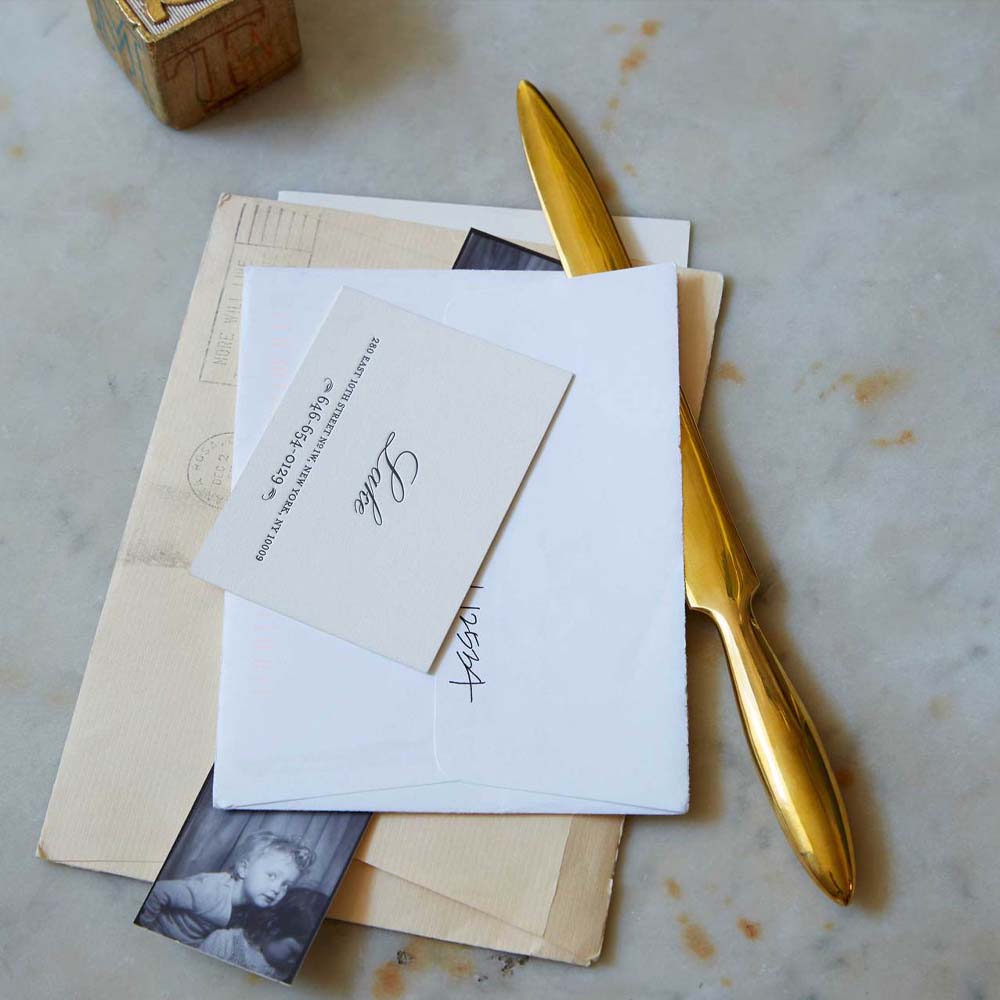 Brass letter opener on a surface with letters and cards