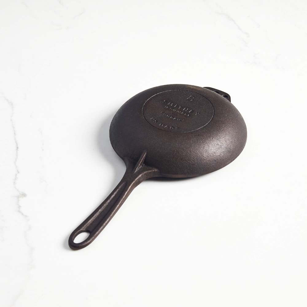 Underside of Smithey eight inch cast iron skillet on a white background