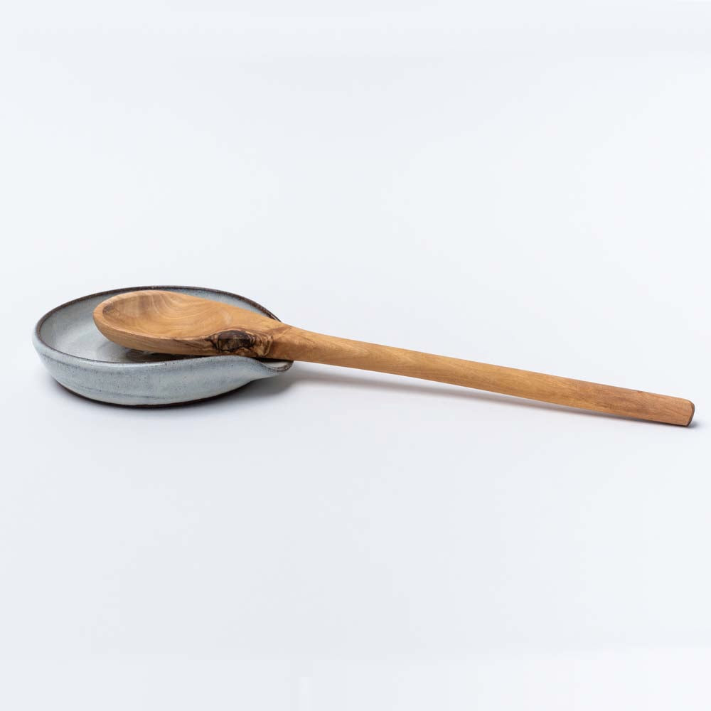 White handmade in Vermont spoon rest with olive wood spoon on a white background