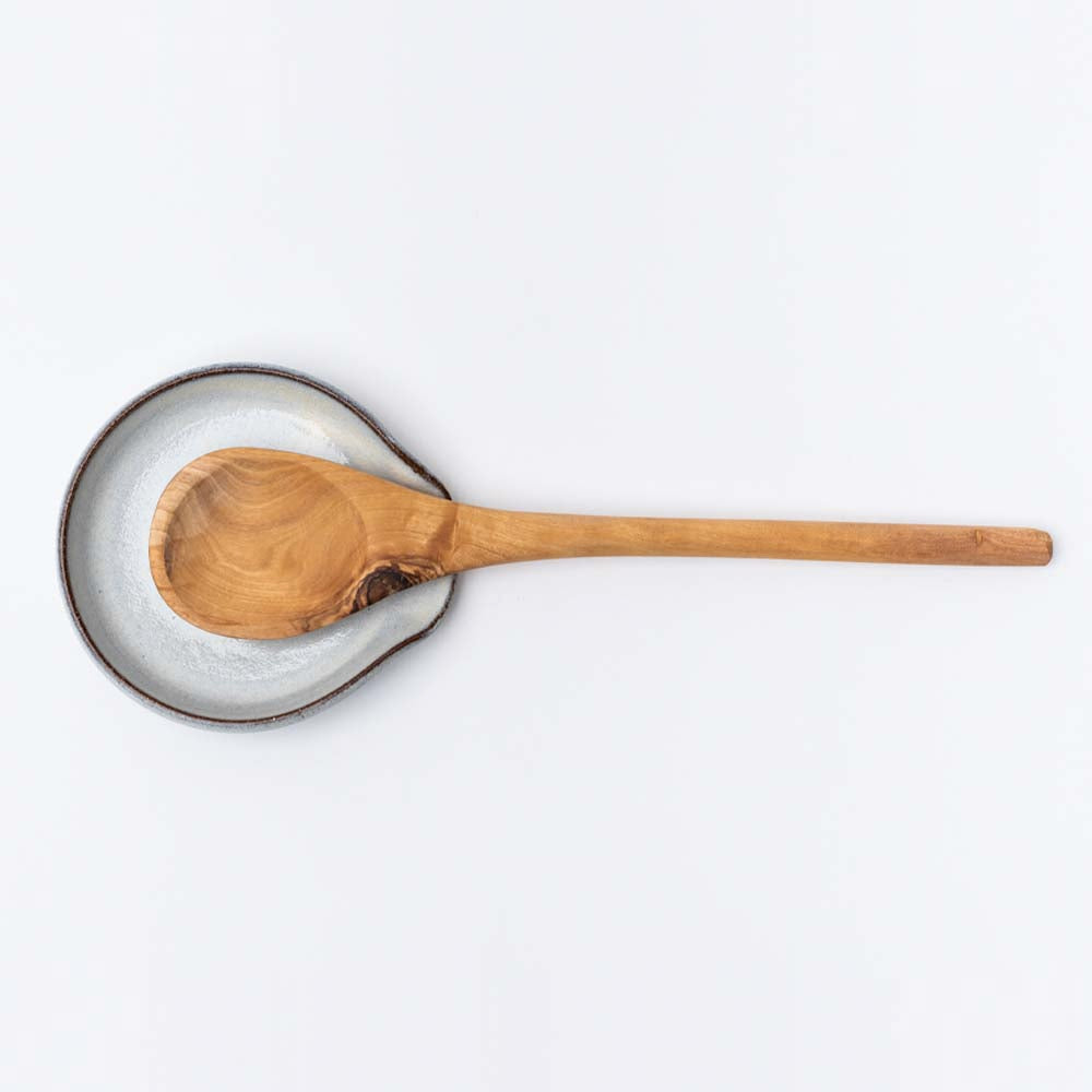 White handmade in Vermont spoon rest with olive wood spoon on a white background