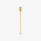 Brass cocktail spoon with base for standing on a white background