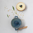 Blue brie baker with bamboo spreader on a counter with baked brie